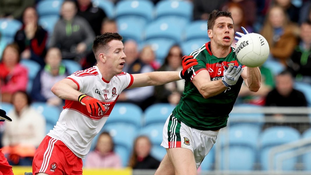 Derry player trying to stop a Mayo man catching the ball