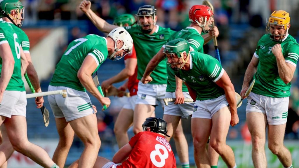 Limerick hurlers surrounding a Cork player on the floor