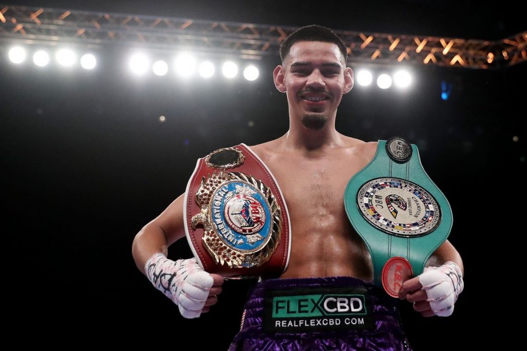 Pro boxer Diego Pacheco celebrating with two belts after a title fight